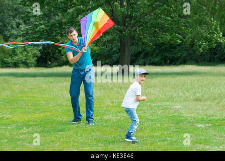 Happy Boy, die die bunten Drachen mit seinem Vater im Park Stockfoto