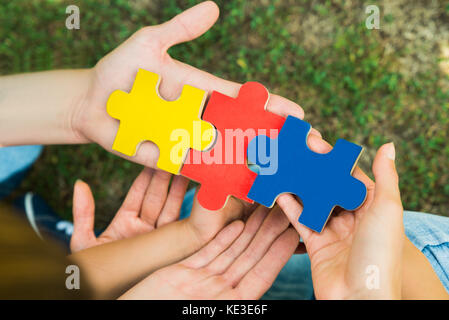 Nahaufnahmen der Hände halten drei bunten Puzzle Stücke Stockfoto