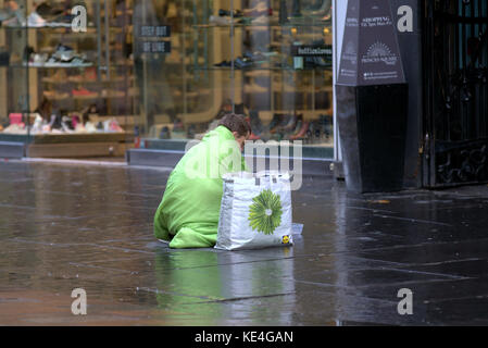 Obdachloser betteln sitzen in Lime Green Schlafsack mit Blume Tasche auf Street Glasgow Großbritannien Stockfoto