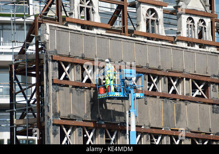 Workman Prüfung nur noch die Fassade eines teilweise zerstörten Gebäude. Stockfoto