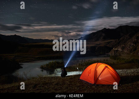 Man Touristen mit Taschenlampe in der Nähe seiner camp Zelt in der Nacht. Stockfoto