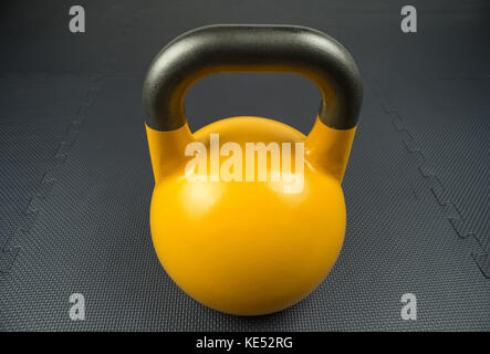 Gelb 16kg kettlebell Wettbewerb auf einem Fitnessstudio Fitnessstudio, mit Gummi Fliesen. Potenzielle text/Raum schreiben in der Mitte des kettlebell. Stockfoto