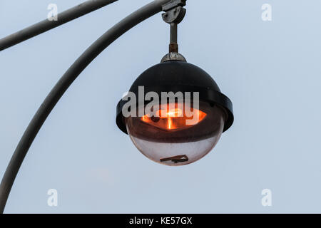 Straßenlaterne arbeitet in einer tagsüber. orange Licht, das Licht grauer Himmel im Hintergrund. industriellen städtischen Szene Stockfoto