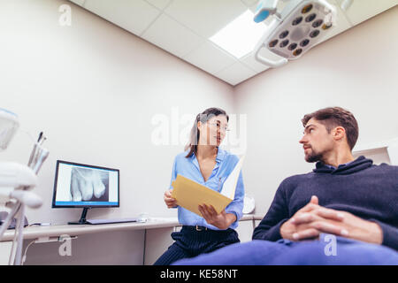 Weiblichen Zahnarzt im Gespräch mit Patienten in der Zahnarztpraxis. Arzt und Patient diskutieren Bericht an den zahnmedizinischen Klinik. Stockfoto