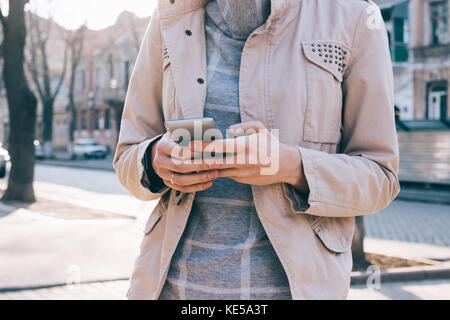 Zugeschnittenes Bild von einer Frau mit einem Handy vor dem Hintergrund der Herbst Stadt Stockfoto