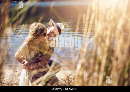 Anhängliches junges Paar, das sich am sonnigen Sommerufer umarmt Stockfoto