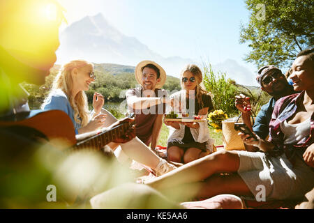 Junge Freunde, die im sonnigen Sommerpark picknicken Stockfoto