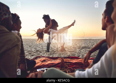 Spielerisches junges Paar, das am sonnigen Sommerstrand tanzt Stockfoto