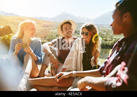 Lächelnde junge Freunde genießen Picknick im sonnigen Sommerpark Stockfoto