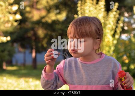 Kleines Mädchen blasen blasen mit grünen Landschaft hinter Stockfoto