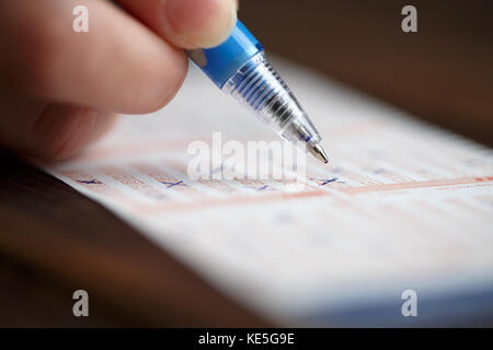 Bild der Person Kennzeichnung in Lottery ticket mit Stift Stockfoto