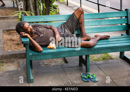 Die Seychellen, Mahe, Victoria, Revolution Avenue, schlechte Seychellois Mann der schläft am Straßenrand Sitzbank Stockfoto