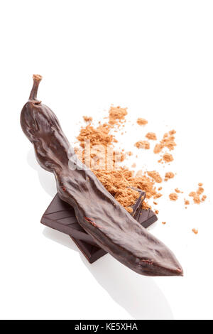 Carob Pulver und Johannisbrot Schokolade auf weißem Hintergrund. Stockfoto