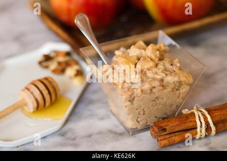 Haferflocken porridge Snack mit Äpfeln, Zimt, Nüssen und Honig auf Marmor Oberfläche Stockfoto