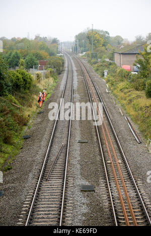 Eisenbahnarbeiter auf dem nicht elektrifizierten Teil der Great Western-Hauptbahnstrecke in Steventon, Oxfordshire, wo eine denkmalgeschützte Brücke über die B4017 die vollständige Elektrifizierung der Strecke verhindert, da sie zu niedrig ist. Stockfoto