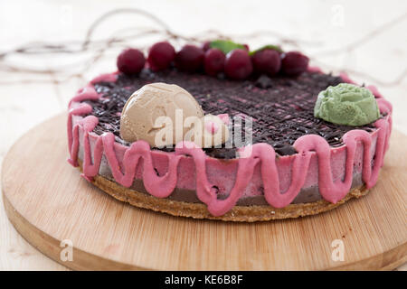 Ein süßer, bunter veganer Kuchen auf einem runden Wollteller, dekoriert mit einem Marienkäfer und einer Blume. Stockfoto