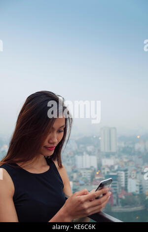Junge asiatische Frau auf ihr Handy Stockfoto