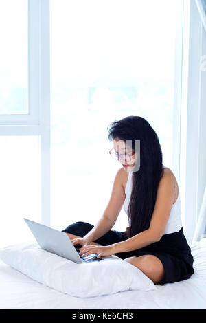 Eine asiatische Frau, die in ihrem Zimmer arbeitet Stockfoto