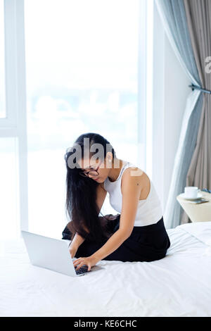 Eine asiatische Frau, die in ihrem Zimmer arbeitet Stockfoto