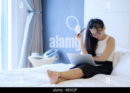 Eine asiatische Frau, die in ihrem Zimmer arbeitet Stockfoto