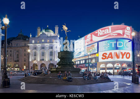 Piccadilly Circus im West End von London. In der Abenddämmerung, Abenddämmerung und am Abend warten Menschen darauf, Freunde unter der Statue von Anteros von Einem Gilbert, London, zu treffen. Stockfoto