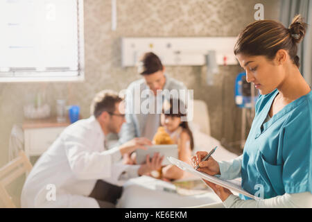 Weibliche Krankenschwester Notizen auf Krankenakte Zwischenablage während Arzt Zeigt ein digitales Tablet für eine Patientin im Krankenhaus Stockfoto