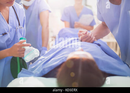 Chirurg hält die Hand des Patienten auf der Bahre Stockfoto