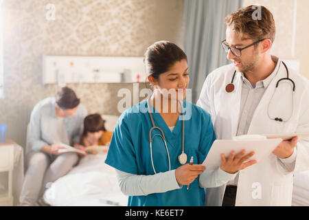 Arzt und Krankenschwester machen Runden im Krankenhaus, Überprüfung der Krankenakte auf Zwischenablage Stockfoto