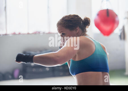 Entschlossenes weibliches Boxer Shadowboxing im Fitnessstudio Stockfoto