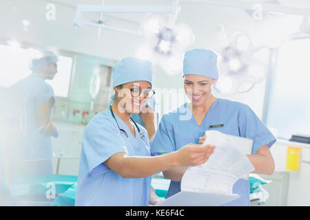 Weibliche Chirurgen Überprüfung Papierkram im Operationssaal Stockfoto
