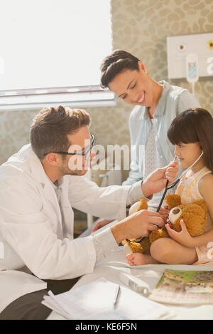 Männlicher Arzt zeigt Stethoskop zu Mädchen Patienten im Krankenhauszimmer Stockfoto