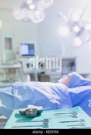 Chirurgische Scheren und Geräte auf Tablett in der Nähe weibliche Patienten in Operationssaal Stockfoto
