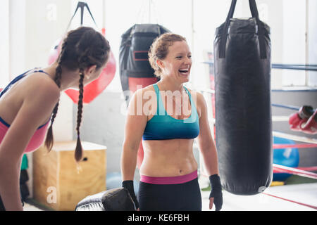 Lachende Boxerinnen neben Boxsäcken im Fitnessstudio Stockfoto