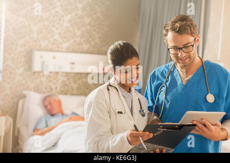 Ärztin und Krankenschwester machen Runden, mit digitalem Tablet und Zwischenablage im Krankenhaus Stockfoto