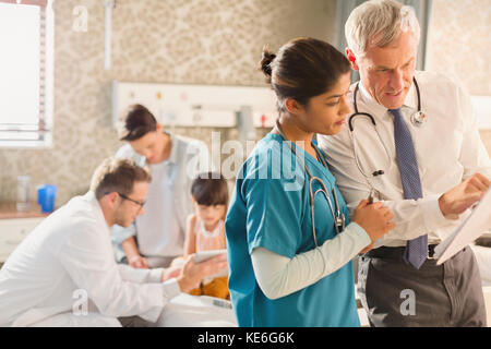 Der Arzt und die Krankenschwester machen Runden und überprüfen die Krankenakte im Krankenhauszimmer Stockfoto