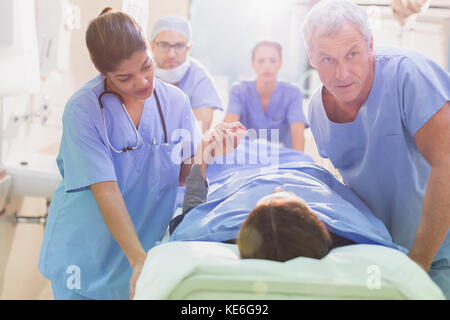 Fürsorgliche Chirurgen, die den Patienten auf eine Bahre im Krankenhausflur schieben Stockfoto