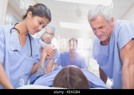 Fürsorgliche Chirurgen sprechen mit dem Patienten auf der Bahre im Krankenhauskorridor Stockfoto