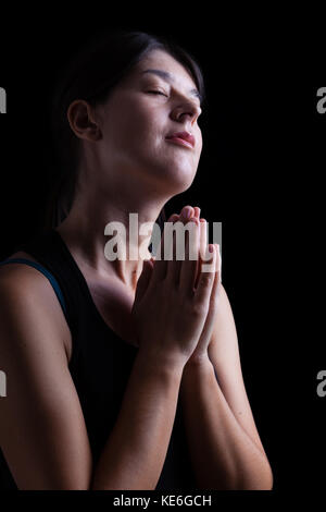 Gerne treue Frau beten und lächelnd in Glück, Glückseligkeit und Frieden, Gefühl mit der Gegenwart Gottes und seiner Gnade inspiriert. Stockfoto