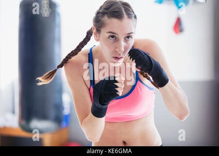 Entschlossenes, hartes junges Boxershadowboxing im Fitnessstudio Stockfoto