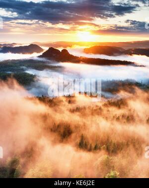 Rosa sunrise in einem schönen Sandstein rocky mountain. scharfen Spitzen von Vollflächen erhöht, der Nebel ist rot und orange aufgrund von heißen Sonnenstrahlen. Stockfoto