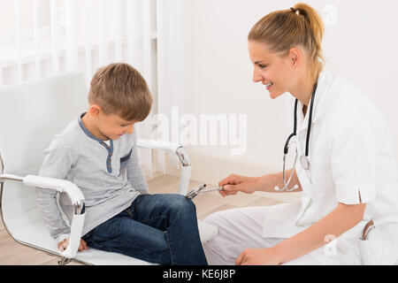 Gerne Ärztin überprüfen Knie Reflex auf ein Kind Patient in der Klinik Stockfoto