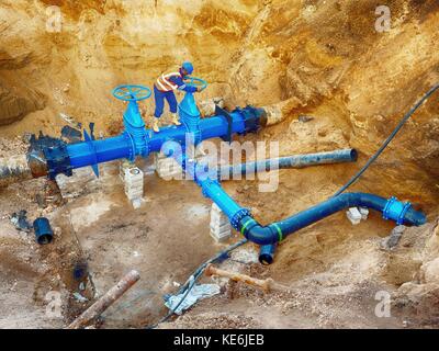 Technische Experten offene Tor Ventil auf 500 mm Wasser trinken Rohre verbunden mit neuen schwarzen spezielle gemeinsame Mitglieder in alte Pipeline System. Kontrollieren von Stockfoto