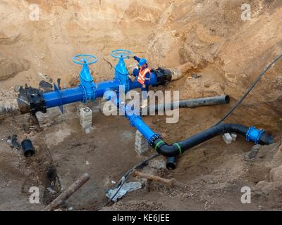 Technische Experten offene Tor Ventil auf 500 mm Wasser trinken Rohre verbunden mit neuen schwarzen Exzenter Verschluss gemeinsame in alte Pipeline System. Mann control Stockfoto