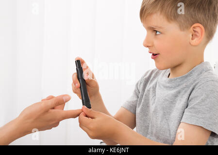 In der Nähe des kleinen Jungen messen Blutzucker der Frau Stockfoto