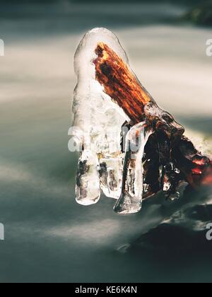 Eiszapfen hängen an Zweigen und eisigen Rinde über Chili rapid Stream. winter Mountain Stream, lange dünne Eiszapfen an gefallenen Stamm hängen. Stockfoto