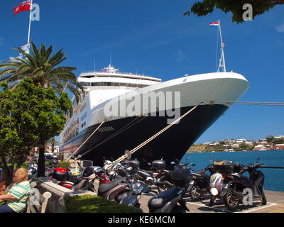 Holland Amerikanisches Kreuzfahrtschiff, Veendam im Hafen von Hamilton, Bermuda, entlang der Front Street. Das allgegenwärtige Bermuda-Symbol, der Roller, ist weit verbreitet. Stockfoto