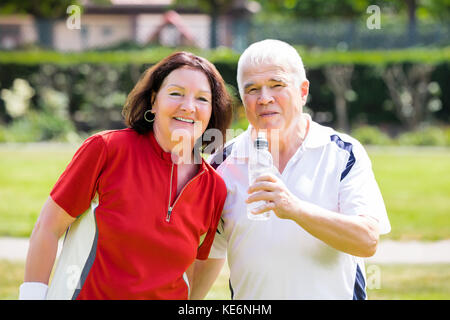 Portrait von Senior Paar Standing In Park Holding Flasche Wasser Stockfoto