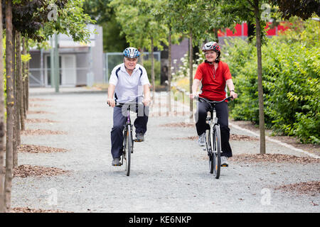 Lächelnde ältere Senior Paar Radfahren im Park am Morgen Stockfoto