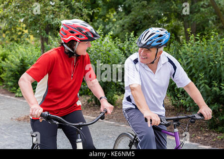 Gerne älteres Paar an jedem anderen Suchen beim Reiten Fahrrad im Park Stockfoto