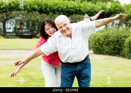 Portrait von lächelnden Senior Paar Fliegen Geste Stockfoto